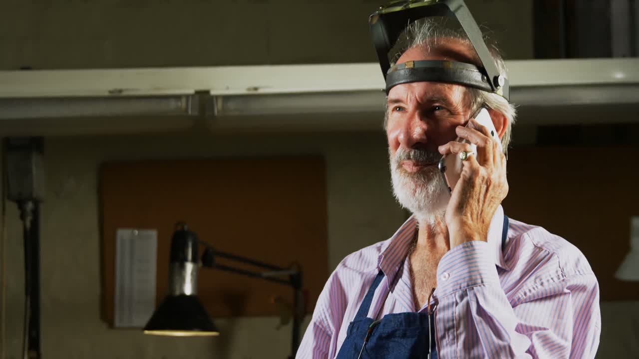 orfebre hablando por teléfono móvil en el taller de trabajo 4k