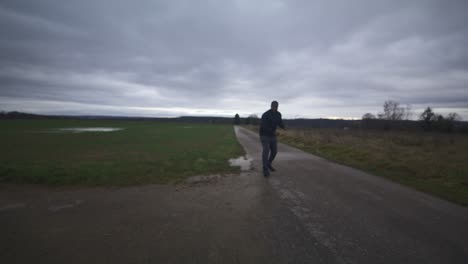 modern black swordsman warrior awaiting battle opponent in open field under grey sky, europe, 4k | muscular, intimidating, shadow, figure, blurry, dark clothes, powerful, very tense, walk to screen