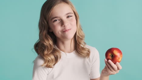 teenage caucasian girl in pijamas eating an apple and smiling.