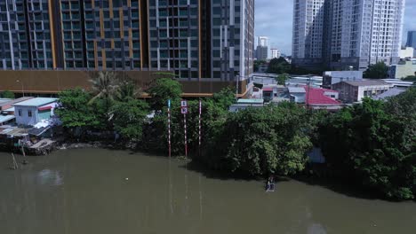 aerial view on kenh te canal ho chi minh city with old iron and wood shacks, traditional river boats and ultra modern high-rise buildings on sunny day