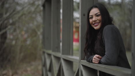 beautiful happy girl smiling on a wooden bridge surrounded by nature and trees