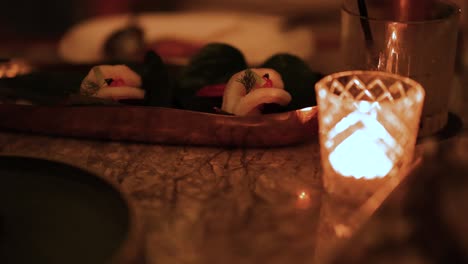a cozy dinner setting with dim lighting, featuring a candlelit table and elegant dishware, creating a warm, intimate atmosphere