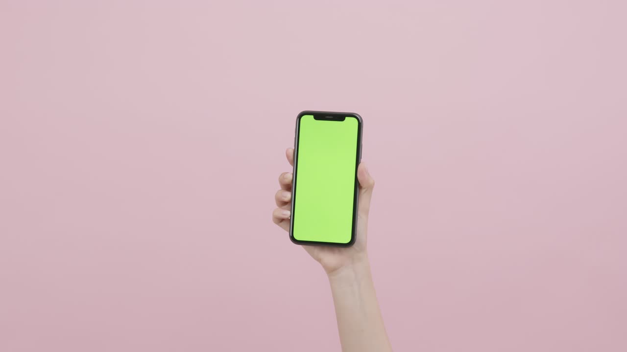 mano sosteniendo un teléfono inteligente con pantalla de tecla de croma y mostrando en el fondo rosa.