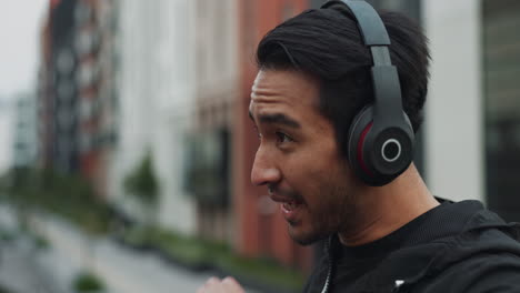 a young man enjoys a drink of water while listening to music in the city