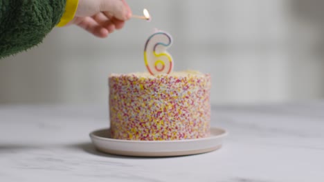 studio shot birthday cake covered with decorations and candle celebrating sixth birthday being lit