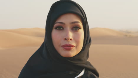 Close-Up-Portrait-Of-A-Beautiful-Muslim-Woman-Wearing-Hijab-And-Looking-At-Camera-In-A-Windy-Desert