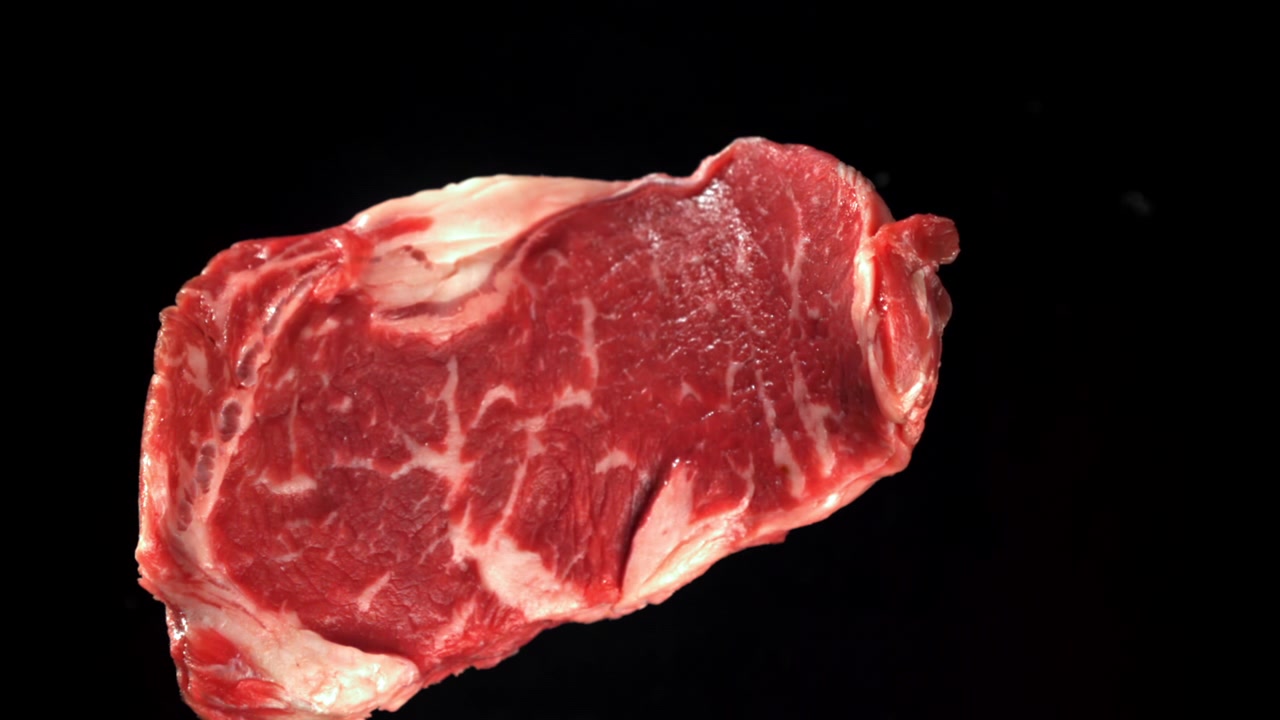 Fresh Raw Ribeye Steak with Marbling on Black Background