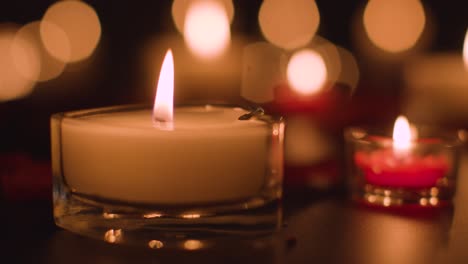 Close-Up-Of-Romantic-Lit-Red-And-White-Candles-Burning-On-Black-Background-With-Bokeh-Lighting-2