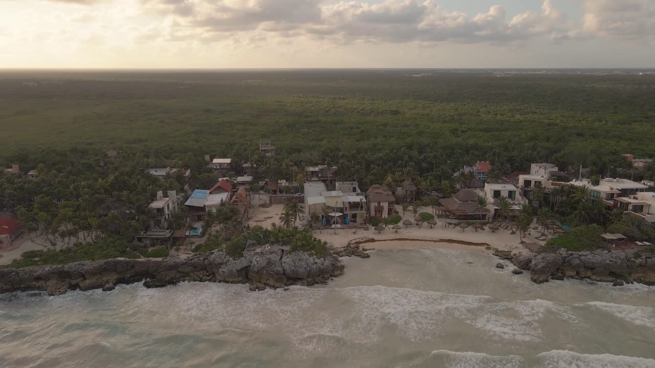 toma de drone de la puesta de sol de una playa paradisíaca en tulum, acercándose a un club de playa