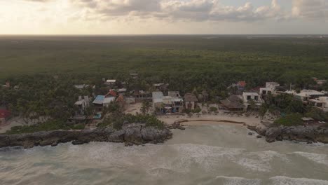 drone shot of the sunset of a paradisiacal beach in tulum, approaching a beach club