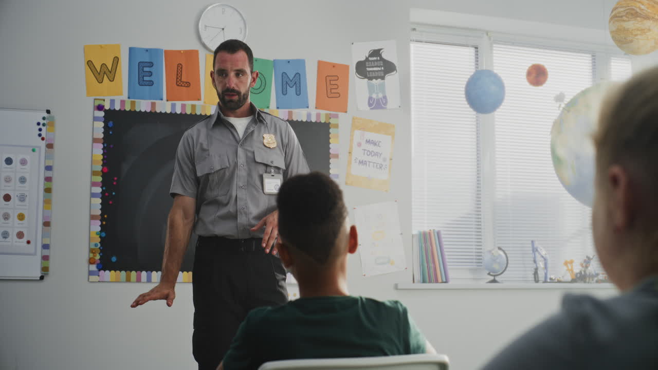 Male Policeman Visiting Classroom Giving Lecture to Curious Primary School Students About Safety