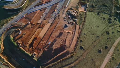 drone reveals a full view of canberra’s highway construction zone with the path of the new road cut through the earth.