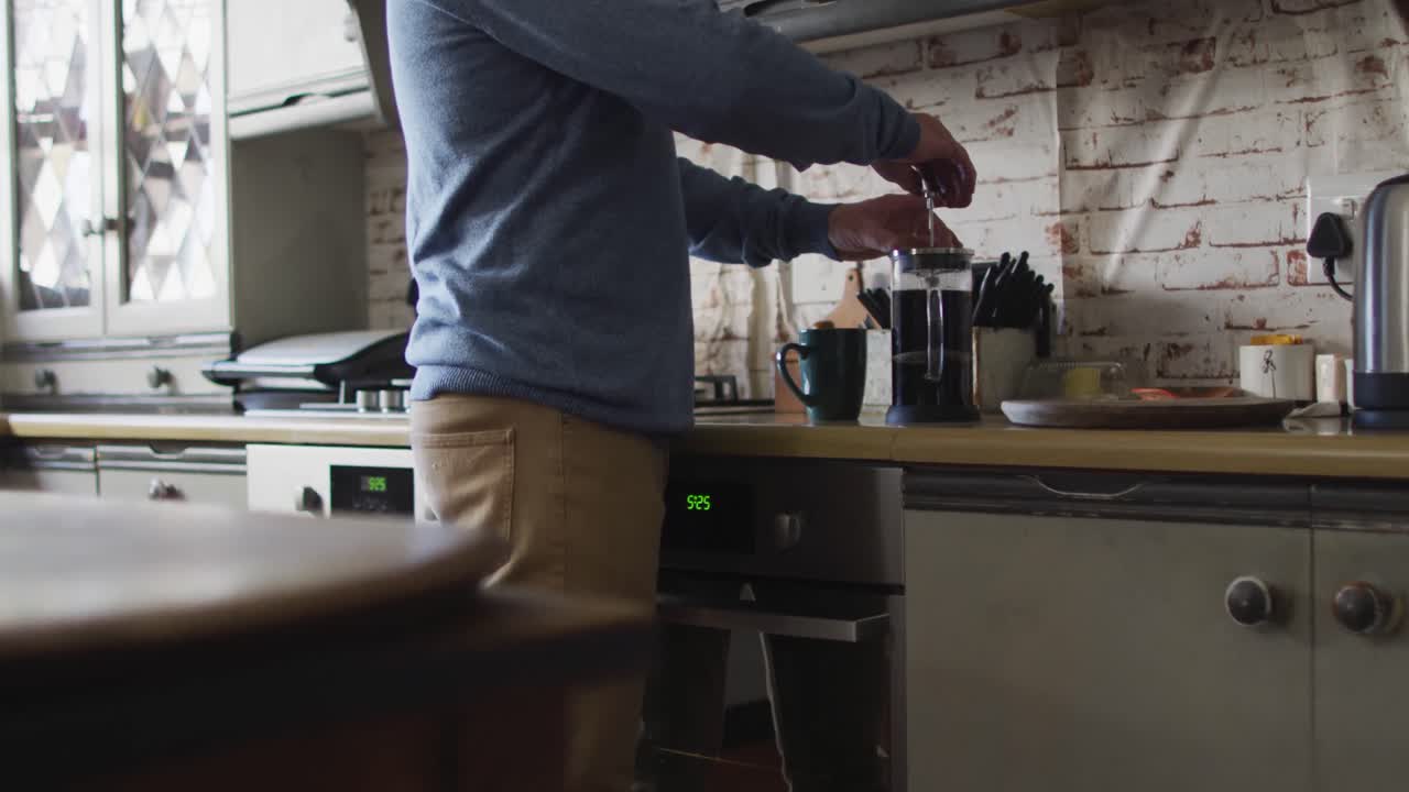 Busto di uomo caucasico che prepara il caffè in cucina a casa.