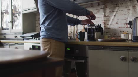 midsection of caucasian man preparing coffee in kitchen at home