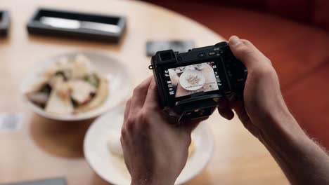 Nahaufnahme-Männlicher-Hände,-Die-Eine-Spiegellose-Kamera-Halten-Und-Essen-Auf-Dem-Tisch-Fotografieren