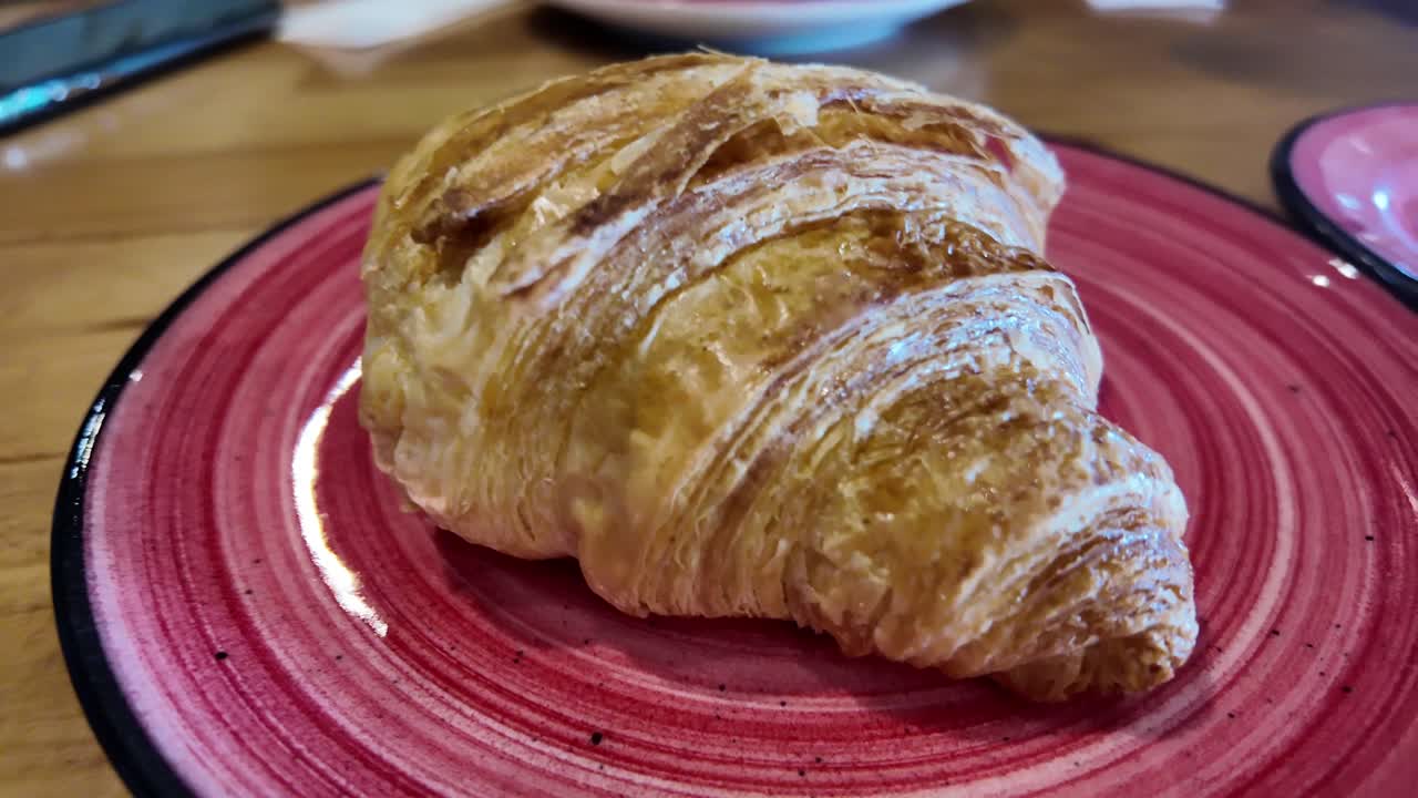 Primo piano di un croissant dorato su un piatto rosso