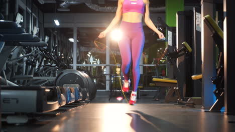 Woman exercising with jumping rope. Young woman exercising using skipping rope in gym