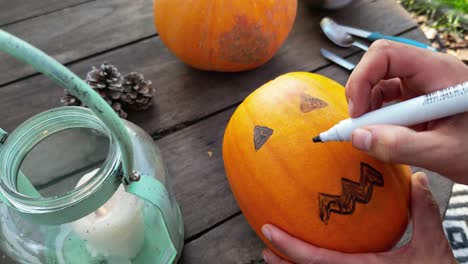 Hands-making-scary-Halloween-pumpkin,-Jack-o-lantern,-designing-the-face