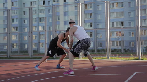 two men playing basketball on an outdoor court