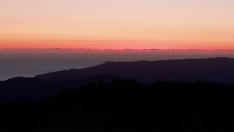 Drohnen-Luftaufnahme-Einer-Bergsilhouette-Bei-Sonnenuntergang-Mit-Orangefarbenem-Himmel