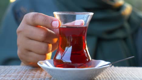 primer plano de una mujer sosteniendo un vaso de té turco