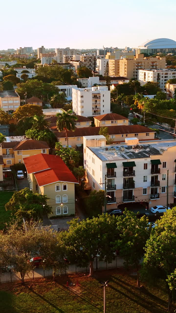 Low-rise buildings with the lush greenery around in the scenery of Miami, Florida, USA. Sunny view of metropolis from top. Vertical video