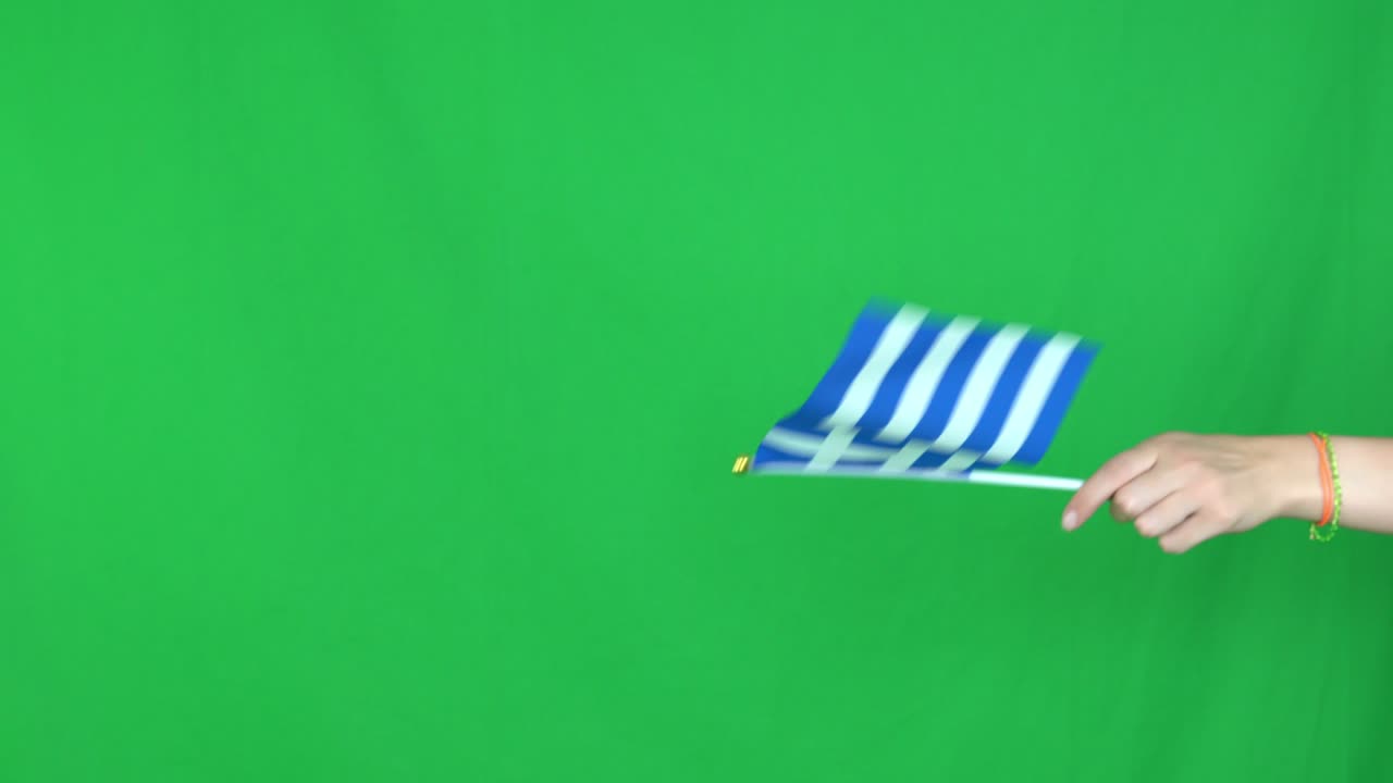 스튜디오의 녹색 화면 배경에 그리스 발을 흔들고 있는 알려지지 않은 손의 근접 촬영입니다.