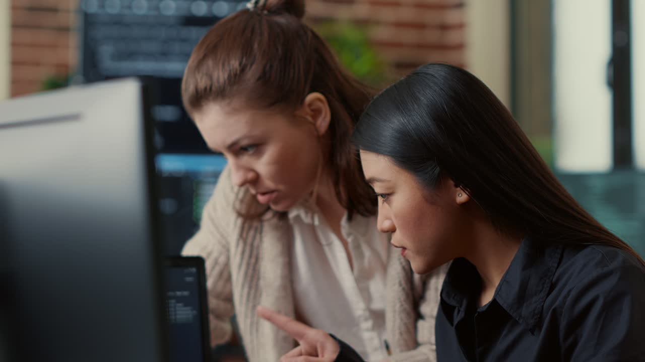 Team of software engineers talking about source code running on laptop screen while sitting at desk