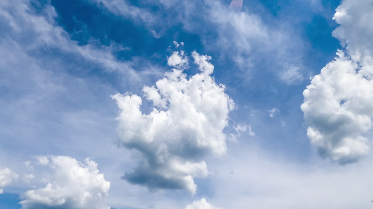 Beautiful fluffy clouds changing shape in the sky. Soft cloudscape in the rays of bright sun timelapse.