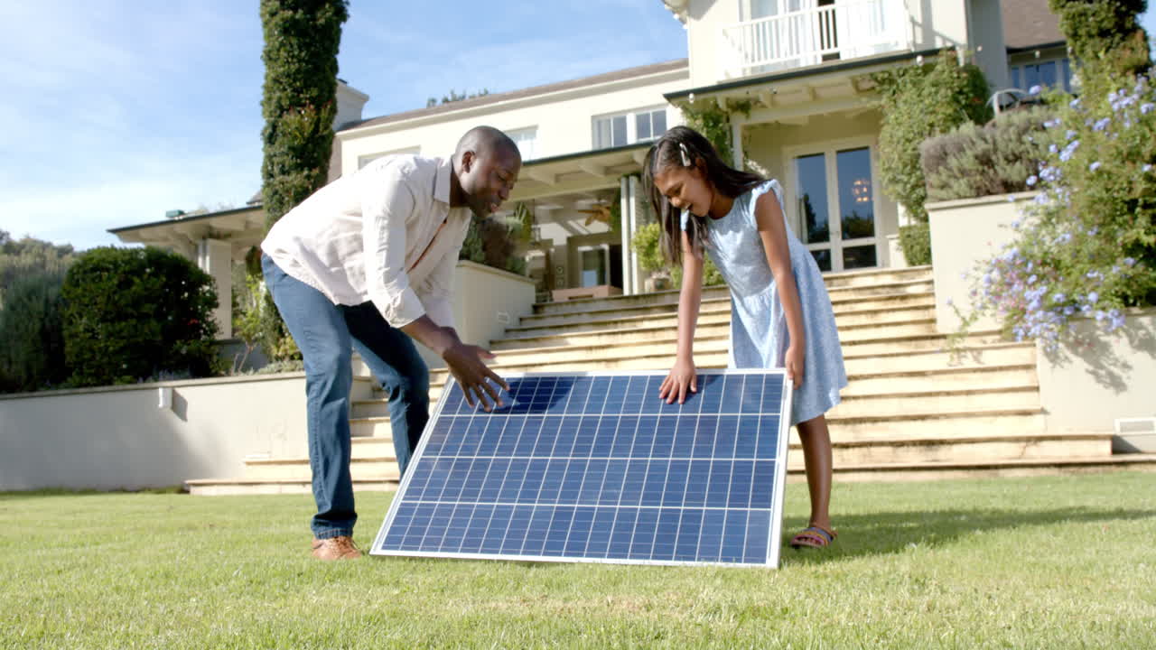 Setting up solar panel, father and daughter working together in front yard