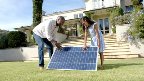 setting up solar panel, father and daughter working together in front yard