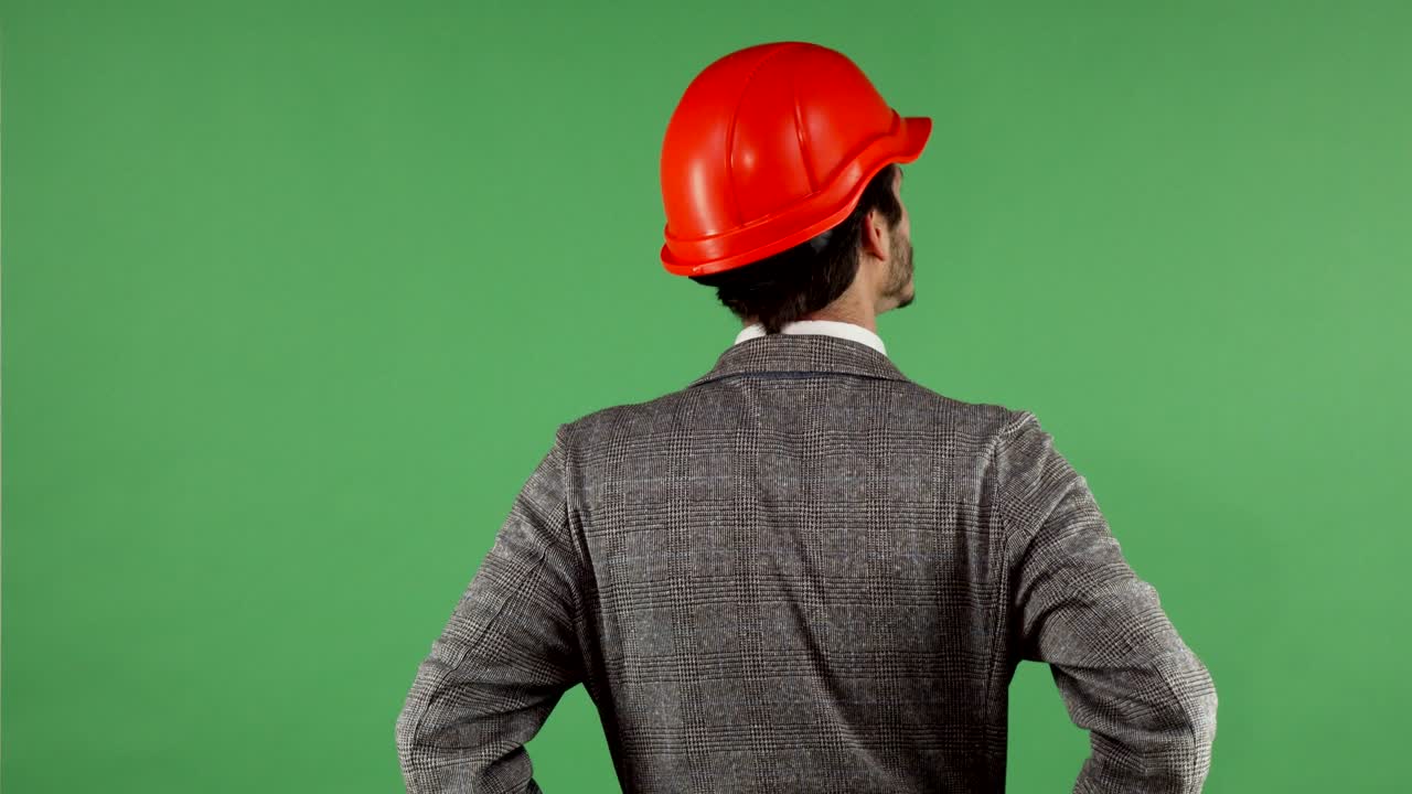 Rear view shot of a contactor wearing hardhat looking around on chromakey