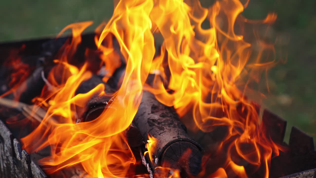 Detailed motion of vivid flame. Twisting tongues of dancing fire. Orange fire flame and slight smoke on blur background. Close-up. Slow motion