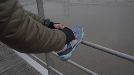 cropped shot of young woman wearing sports clothing tying shoelace