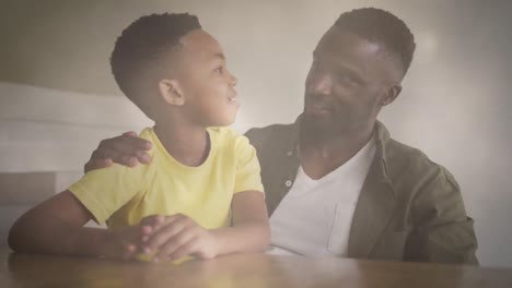 Animation-of-lights-over-happy-african-american-father-and-son-talking