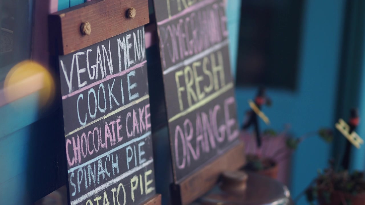 Nærbillede af en cafés veganske menu og tavler med frisk juice