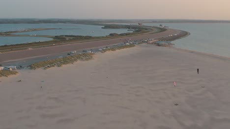 drone cinemático - toma aérea de la playa natural verde y arenosa al atardecer con turistas y personas con buggykiting en zelanda en el mar del norte, países bajos, 30p