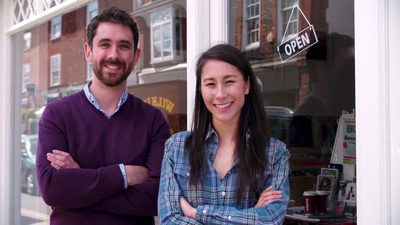 dueños de tiendas de pie frente a una ventana de la tienda