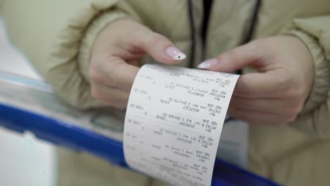 the buyer holds a purchase receipt in his hands, checks purchases and prices