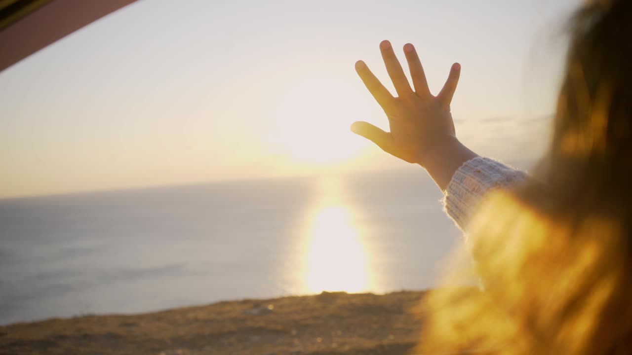mujer balancea las manos fuera de la ventana del coche y agita la mano