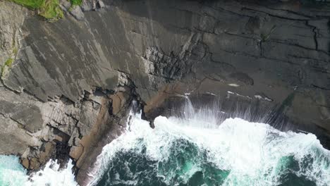 tomada aérea de un dron que revela los acantilados costeros de kilkee en irlanda donde las olas se aplastan contra los altos acantilados rocosos