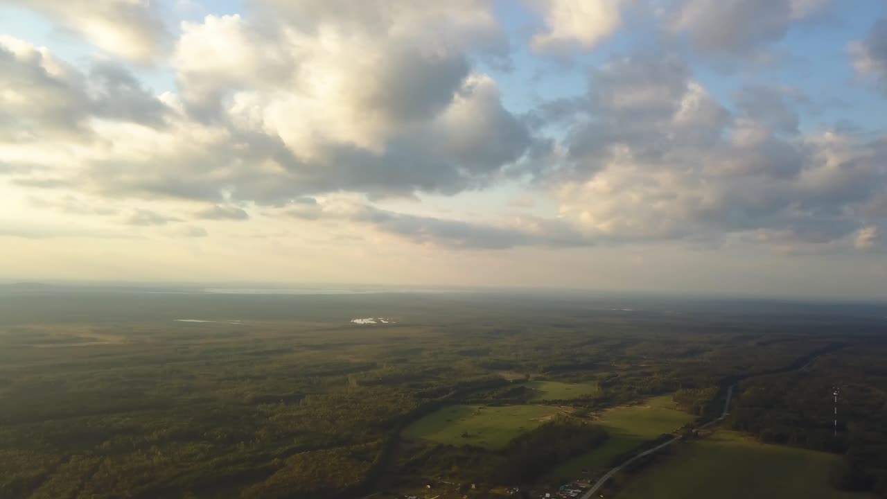 vista aérea de un paisaje con bosques, lagos y nubes