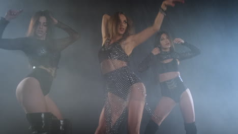 three women dancing in a smoky nightclub