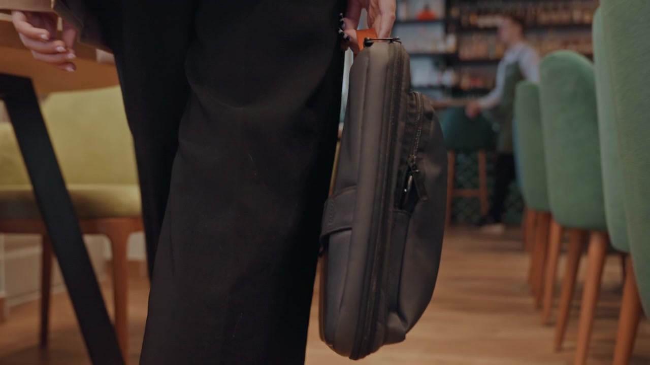 Caucasian executive walking with briefcase through cozy cafe, green chairs, wooden floor, warm lighting, business attire, steady pace, hand gripping leather bag, quiet morning commute, contemplative