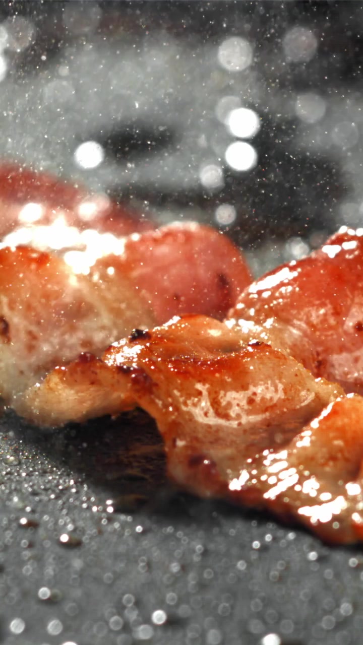 Primo piano di striscioline di pancetta croccante che friggono in una padella calda