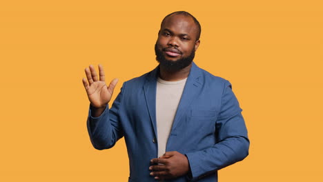 man reluctantly doing salutation hand gesture, saying goodbye, studio background