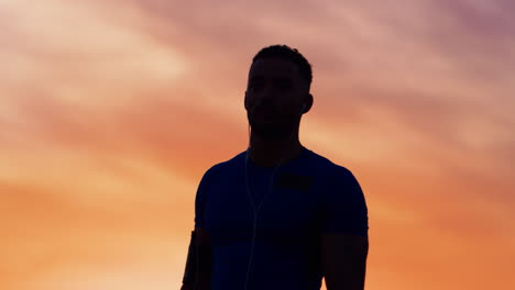 silhouette of male athlete crossing arms at sunset, waist up