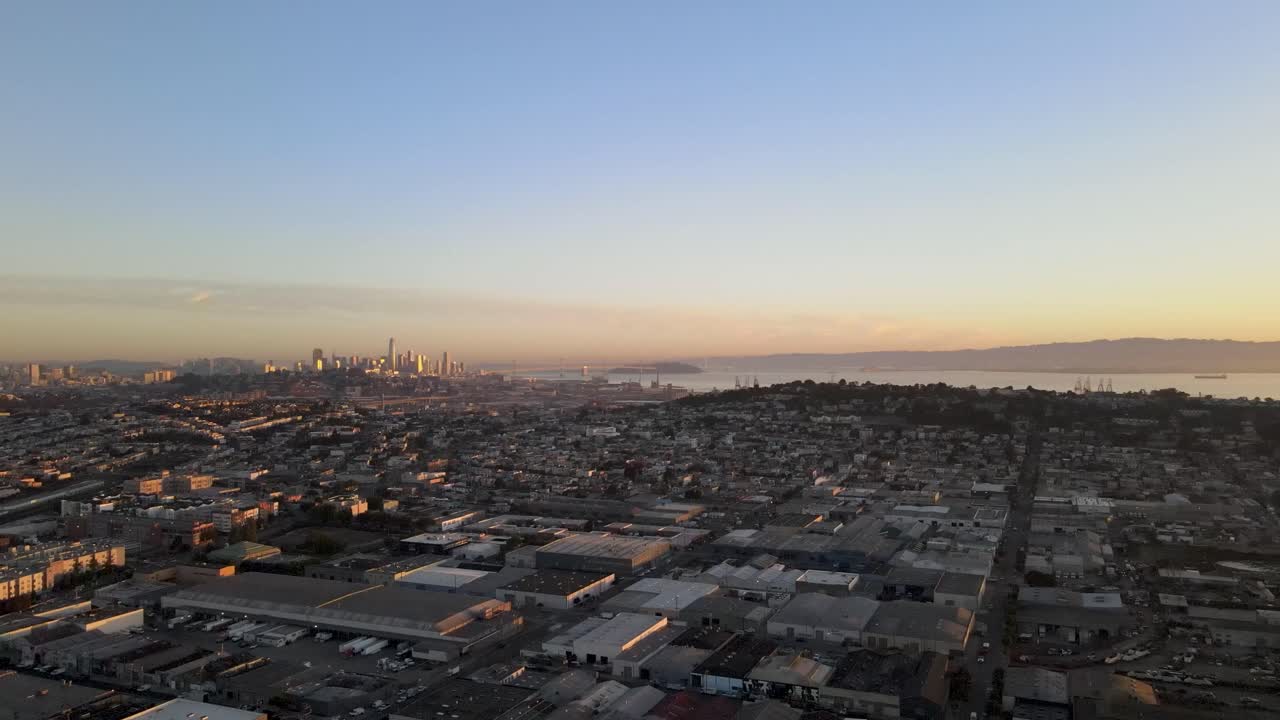A tranquil drone retreats slowly, providing an enchanting perspective over a San Francisco neighborhood with the backdrop of downtown buildings immersed in the morning's golden glow