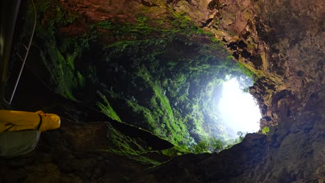 tourist explores algar do carvao volcanic tube in terceira, azores