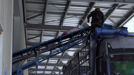 chemical fertilizer, sugar, flour, and rice sacks stacked up bags on a conveyor belt in large warehouse to truck for distribution to customer, import export logistics business.